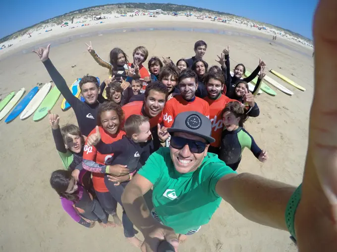 Treinadores e crianças juntos na areia a seguir a uma aula, com as pranchas alinhadas atrás